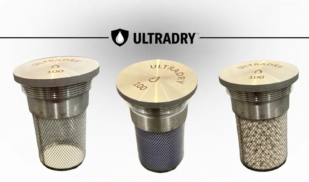 Three ULTRADRY 100g desiccant cartridges with 8mm  stainless steel mesh bodies and circular metal tops, shown side by side, 1 empty 1 with blue silica 1 with white zeolite, on a light gray background with the ULTRADRY logo above.