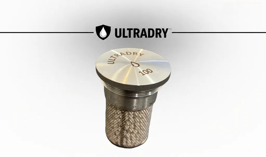 An ULTRADRY 100 gram zeolite molecular sieve cartridge, featuring a stainless steel top cap with the ULTRADRY brand name and '100' engraved on it, and a textured mesh body that allows the encapsulated molecular sieve or desiccant to breath, shown against a white background with an ULTRADRY logo banner at the top.