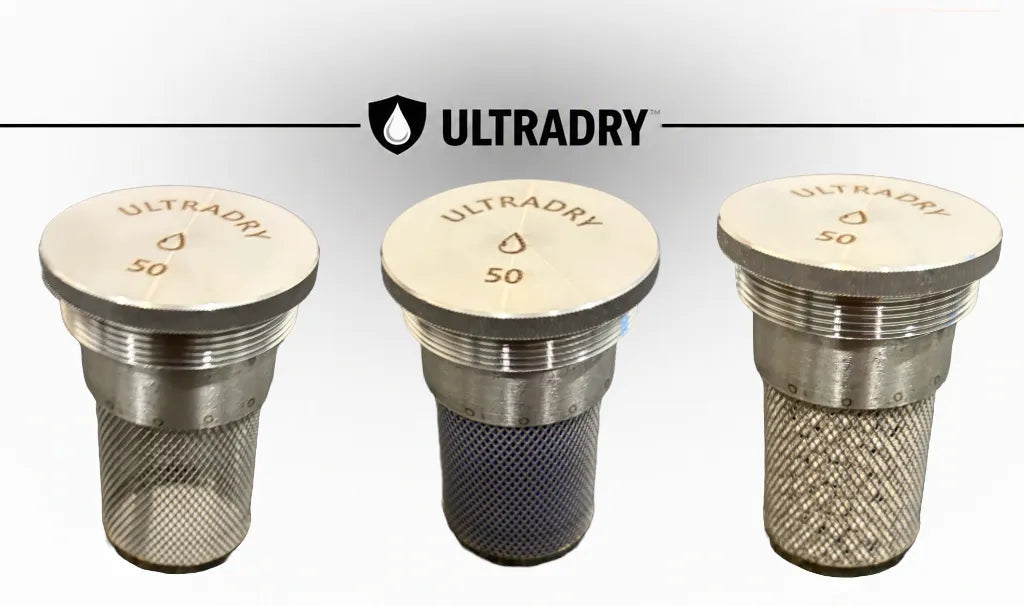 Three ULRADRY 50 gram moisture absorber stainless steel ports with 8mm mesh, displayed side-by-side on a white background, 1 empty 1 with blue silica 1 with white zeolite, with the ULRADRY brand logo at the top.